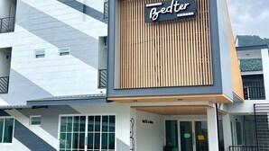 Een modern hotel met een geometrisch gevelontwerp, een opvallend bord waarop 'Bedter Hotel' staat en een nette entree met een glazen deur.