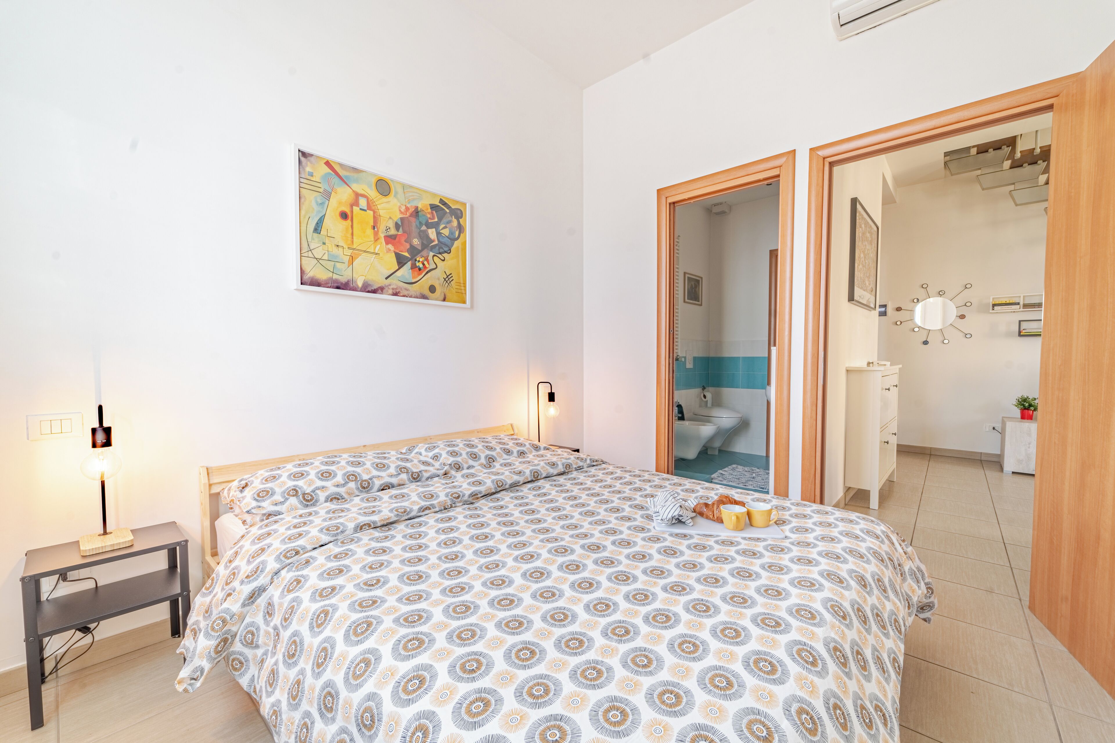 Une chambre à coucher avec un lit, une table de chevet, une lampe et un tableau au mur.