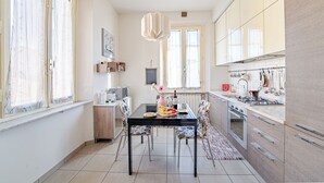 Una cocina moderna con una mesa de comedor, sillas y una lámpara colgante.
