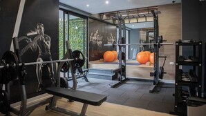 Une salle de sport équipée de matériel de musculation, d’un banc et de ballons d’exercice.