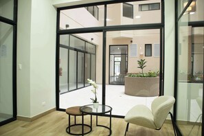 Un espacio de oficina moderno con paredes de vidrio, una mesa redonda con un florero y una silla cómoda.