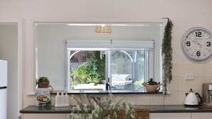 A kitchen with a window, a clock, and a kettle.