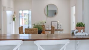 A dining area with a wooden table, white chairs, a round mirror, and a potted plant.
