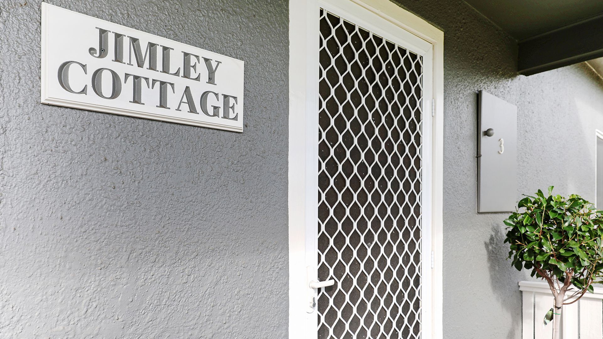 A house sign reading 'JIMLEY COTTAGE' and a lattice door.