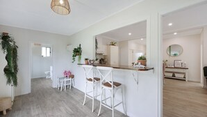 A modern kitchen with white cabinetry, a wooden countertop, and a hanging light fixture.