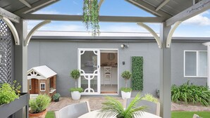 A covered patio with a white door, potted plants, and a small wooden structure.