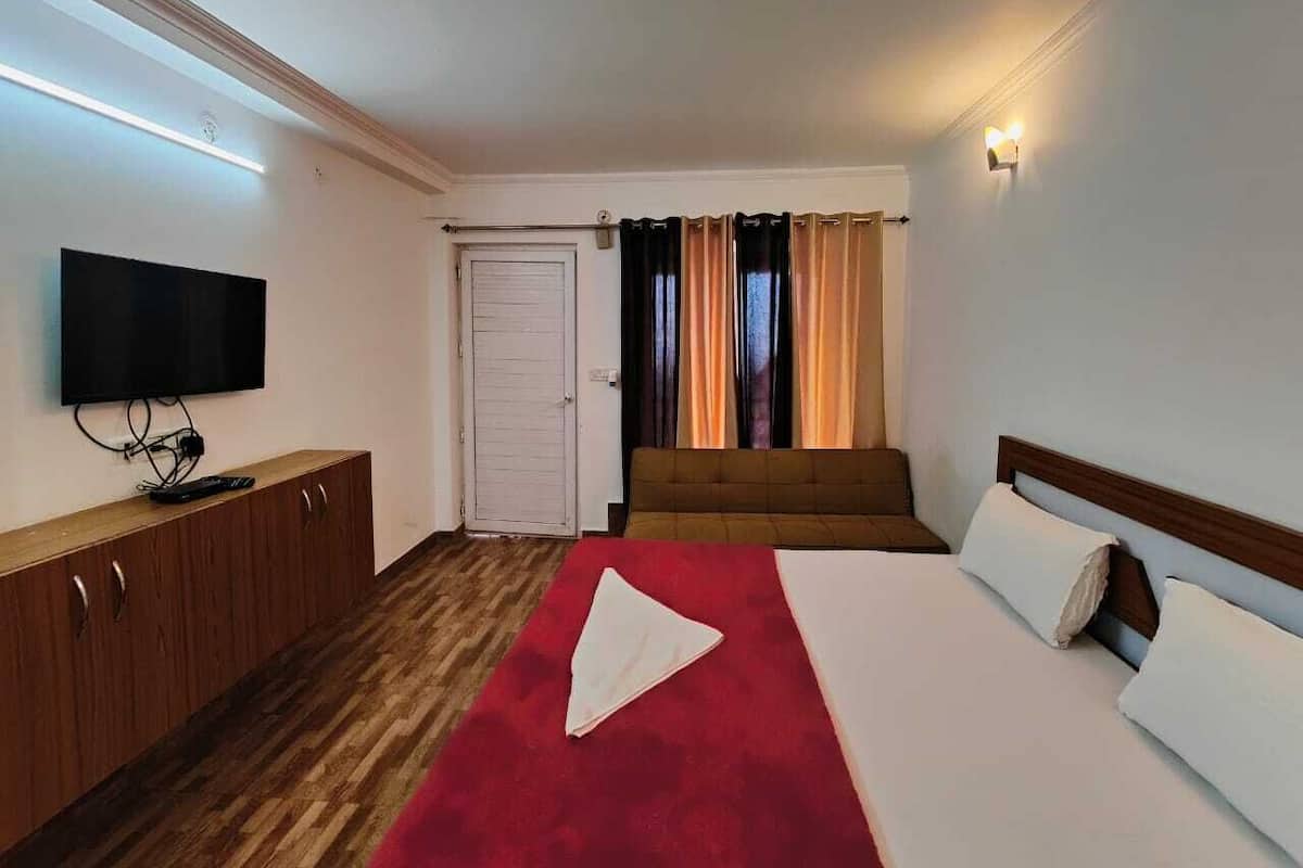Une chambre d’hôtel avec un lit, une télévision, une armoire en bois et une porte.