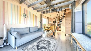 A modern interior with a grey sofa, a patterned rug, and a 'Welcome' sign on the wall. - Domek Freedom Sun & Snow (gmina Wolin)