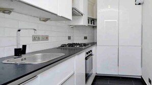 A modern kitchen with white cabinets, a stainless steel sink, and a black countertop. -  Spacious -First Floor- 4 beds -2 bath (London)