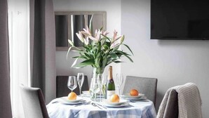 A dining table set with a blue and white checkered tablecloth, a vase of flowers, wine glasses, and a bottle of champagne. -  Spacious -First Floor- 4 beds -2 bath (London)