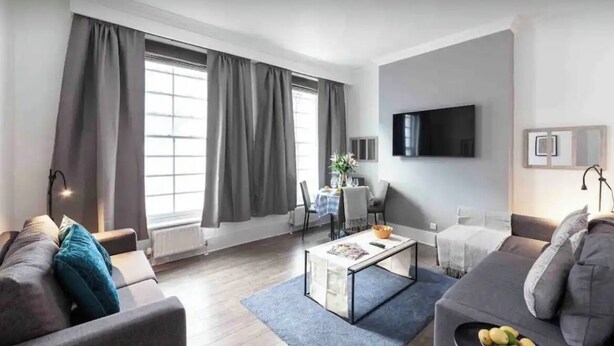 A modern living room with a sofa, a coffee table, and a TV mounted on the wall. -  Spacious -First Floor- 4 beds -2 bath (London)