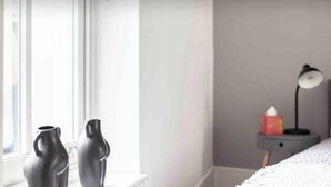 A bedroom with a bed, a nightstand with a lamp, and two vases on the windowsill. -  Spacious -First Floor- 4 beds -2 bath (London)