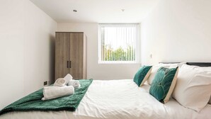 A bedroom with a bed, a wardrobe, and a window with blinds. - Bright 1 Bed Apartment in Yeadon (Yeadon)
