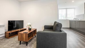 A modern living room with a flat-screen TV, a wooden coffee table, and a grey sofa. - Bright 1 Bed Apartment in Yeadon (Yeadon)