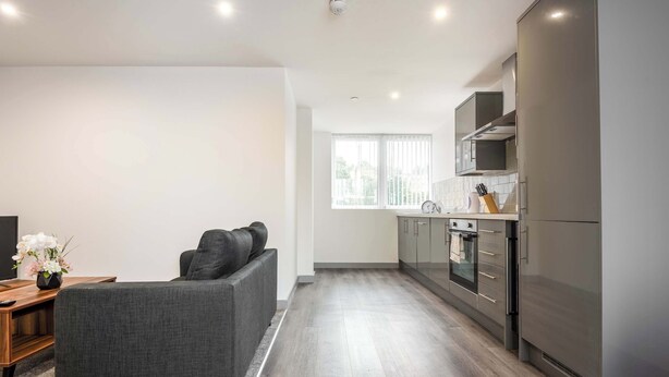 A modern kitchen with grey cabinets, a stainless steel refrigerator, and a window with blinds. - Bright 1 Bed Apartment in Yeadon (Yeadon)