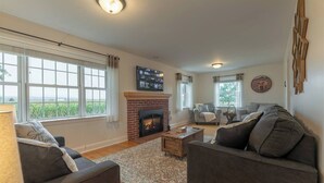 Ein Wohnzimmer mit Kamin, zwei Sofas, einem Couchtisch und einem an der Wand befestigten Fernseher.