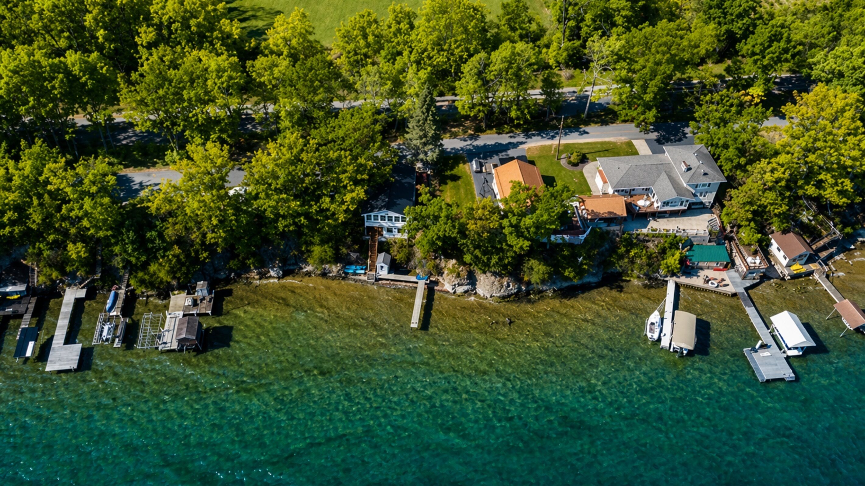 An aerial view of a lakeside property with a house, dock, and boats.