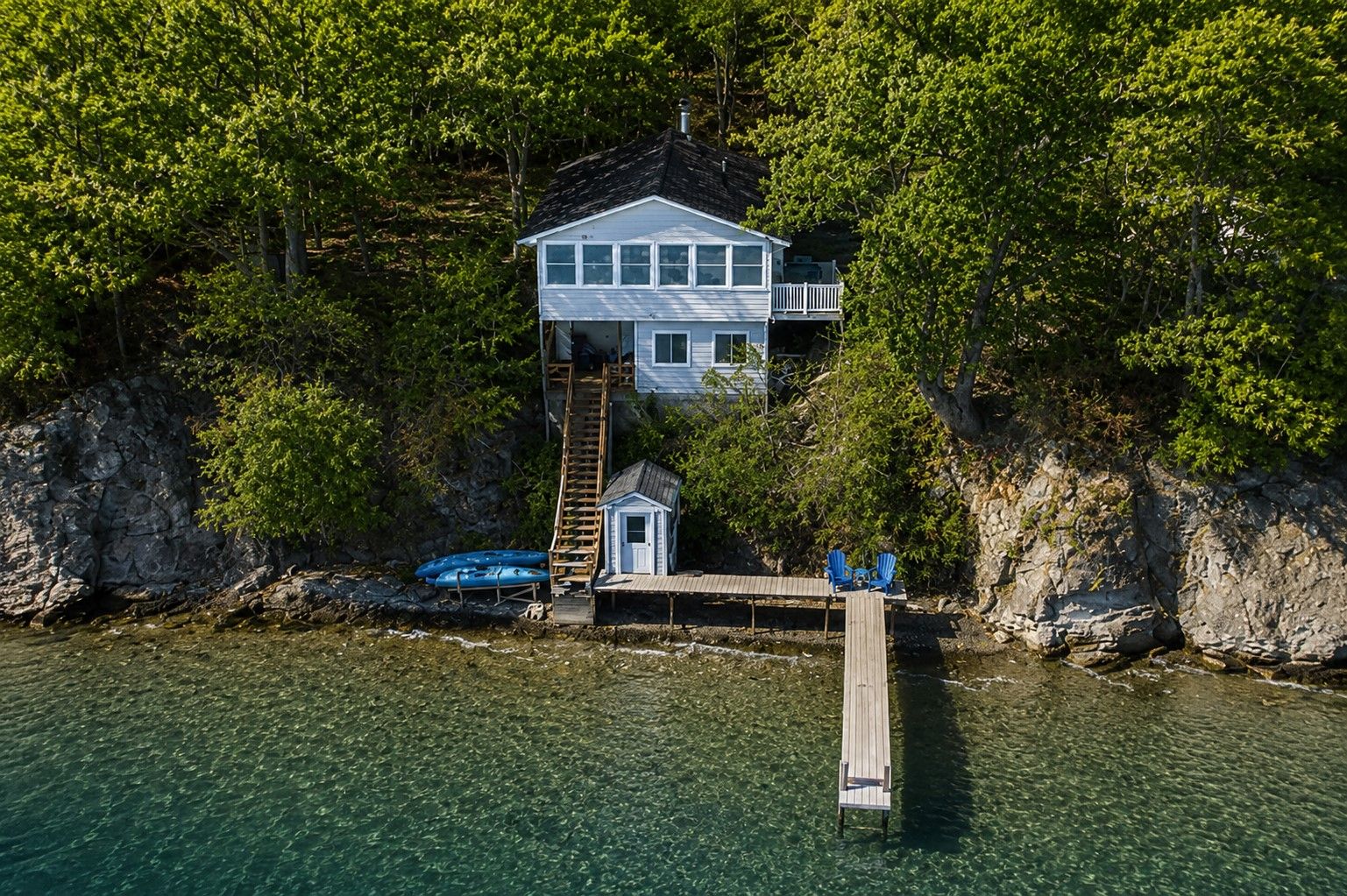 A house with a dock extending into a lake, surrounded by trees.