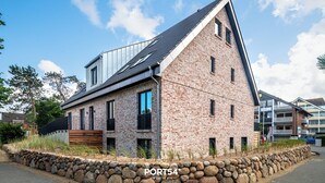 A modern brick building with a sloped roof and large windows. - "Arriving" in the heart of St. Peter-Ording (Sankt Peter-Ording)