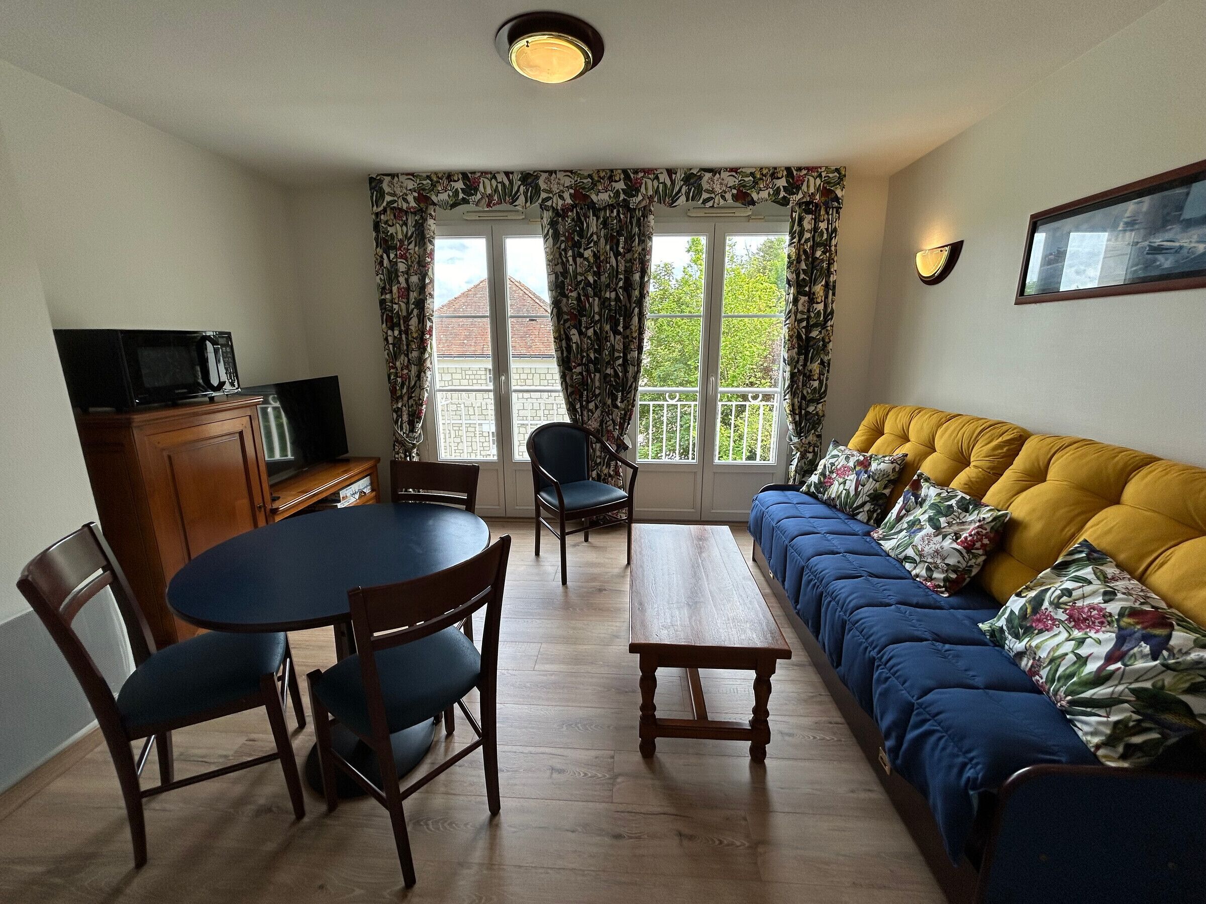 A living room with a sofa, chairs, a dining table, and a television.