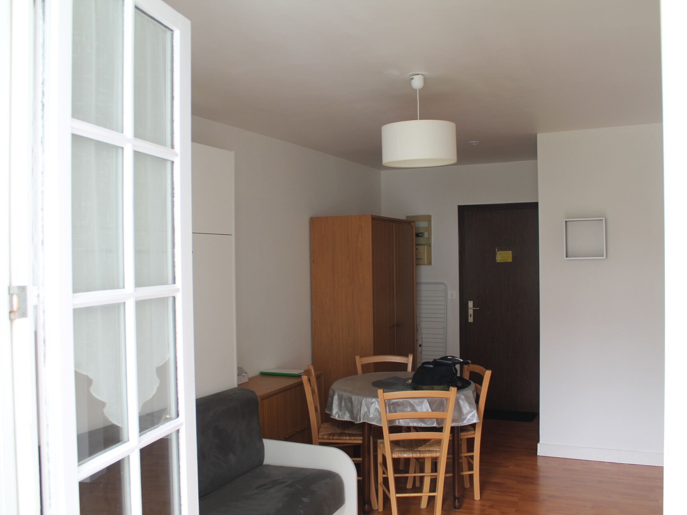 A room with a dining table, chairs, a sofa, a cabinet, and a door.