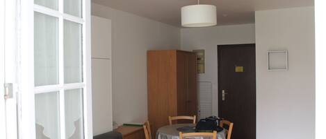 Una habitación con una mesa de comedor, sillas, un sofá, un armario y una puerta.