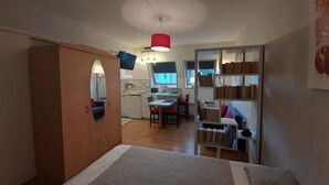 A compact room with a bed, a desk, and a kitchenette.