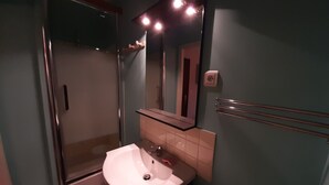 A bathroom with a glass shower enclosure, a white sink, and a mirror above it.