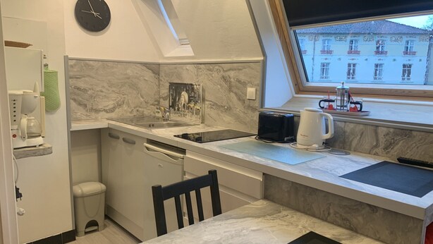 A compact kitchen with a sink, a coffee maker, a toaster, and a window with a view of buildings.