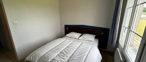 A bedroom with a bed, a window, and a radiator.