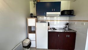 A compact kitchen with a microwave, stove, and cabinets. - T2 Apartment with Wi-Fi and Pool 200m from Spas (La Roche-Posay)