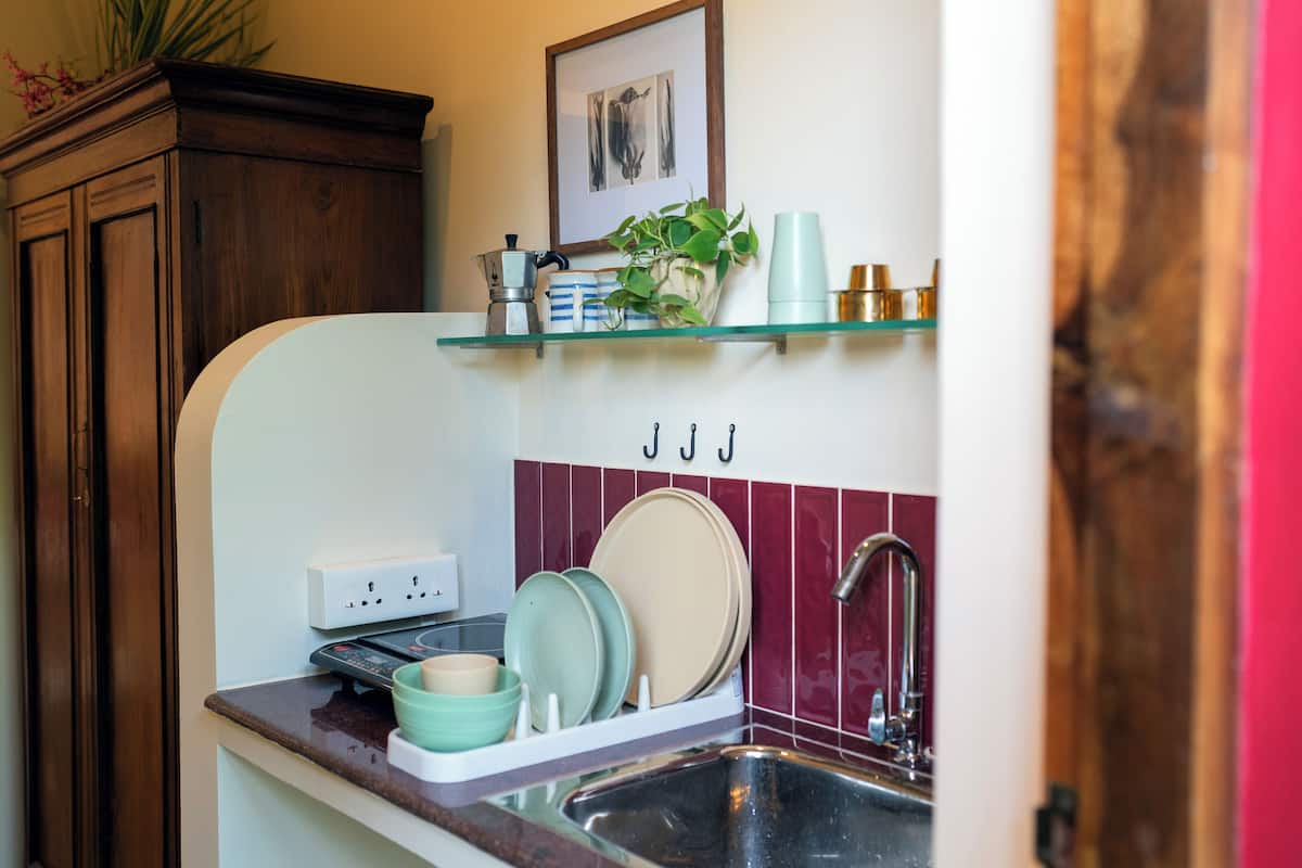 A kitchen with a sink, countertop, and a shelf above it.