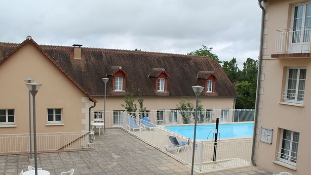 A courtyard with a swimming pool, outdoor seating, and a building with multiple windows and balconies. - Lovely apartment 170m from thermal baths - 5 guests (La Roche-Posay)
