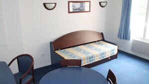 A room with a bed, a round table, two chairs, a window with a curtain, and wall-mounted lights. - Lovely apartment 170m from thermal baths - 5 guests (La Roche-Posay)