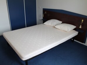 A single bed with a wooden headboard, a white mattress, and two pillows. - Lovely apartment 170m from thermal baths - 5 guests (La Roche-Posay)