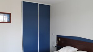 A bedroom with a bed, a nightstand, a blue wardrobe, and a framed picture on the wall. - Lovely apartment 170m from thermal baths - 5 guests (La Roche-Posay)