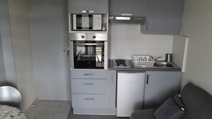 Uma cozinha compacta equipada com forno embutido, micro-ondas e frigorífico.