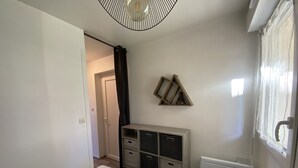 A bedroom with a bed, a dresser, a radiator, and a wall-mounted shelf with a statue. - 1-bedroom apartment with terrace and Wi-Fi near Connétable Thermal Baths (La Roche-Posay)