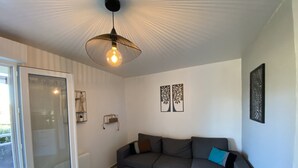 A modern living room with a grey sofa, a round wooden coffee table, and a pendant light. - 1-bedroom apartment with terrace and Wi-Fi near Connétable Thermal Baths (La Roche-Posay)