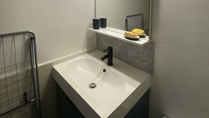 A bathroom with a white sink, a mirror with lights, a towel rack, and a toilet. - Charming T2 with terrace near Thermes du Connétable, Wi-Fi, dishwasher (La Roche-Posay)