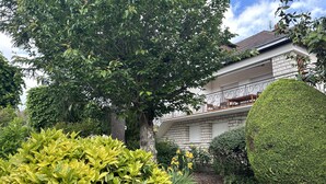 A house with a balcony, surrounded by lush greenery and a well-maintained garden. - City center T3 apartment with garden and air conditioning (La Roche-Posay)
