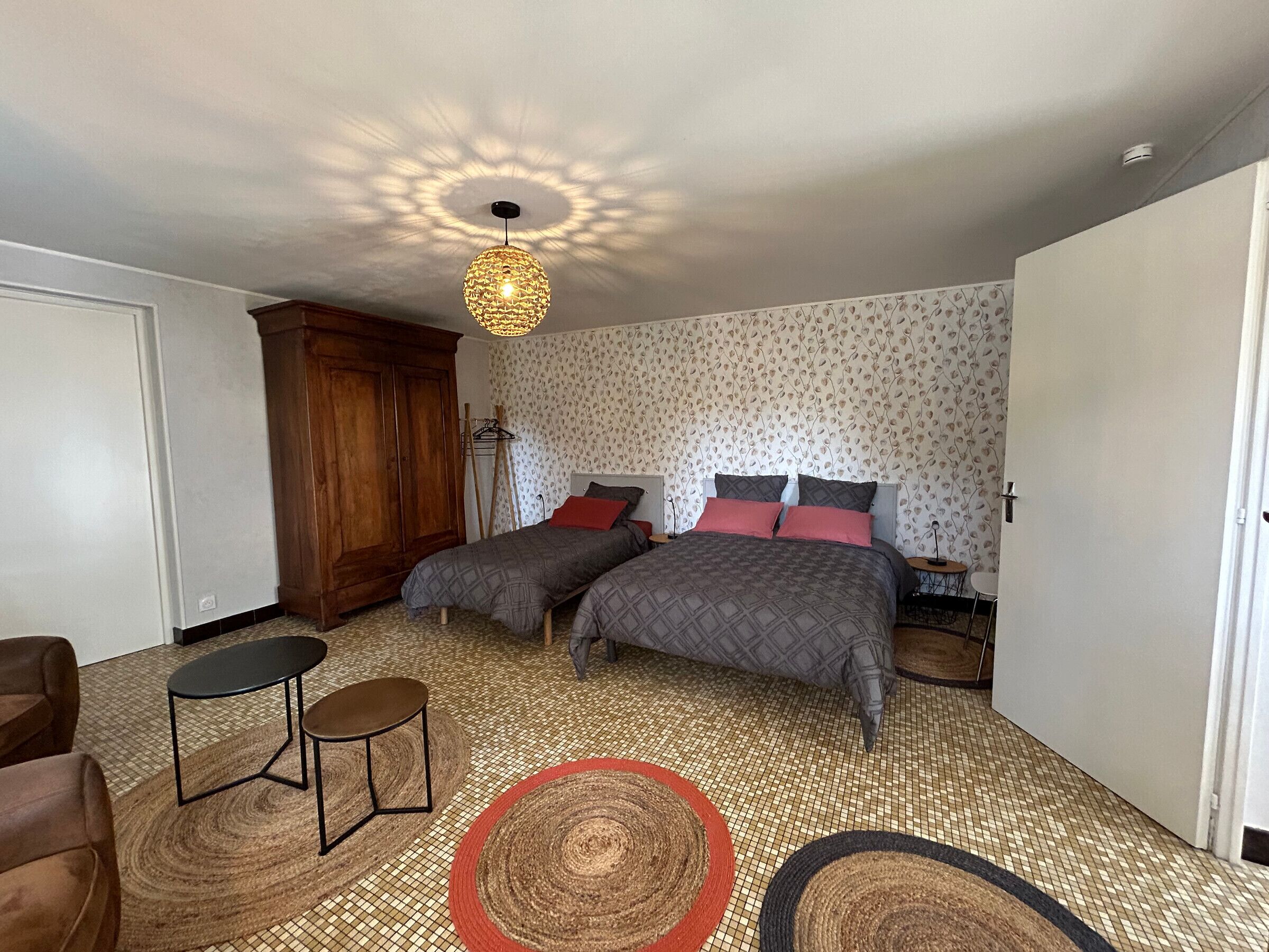 A bedroom with two beds, a wardrobe, a small table, and a floor lamp.