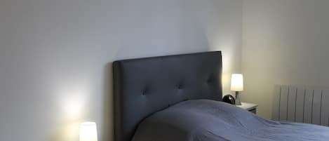 A bedroom with a large bed, two bedside tables, and a radiator.