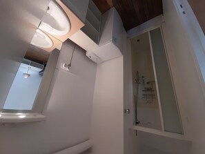 A modern bathroom with a toilet, a shower, and a window.