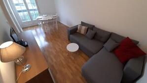 A modern living room with a grey sofa, a wooden coffee table, and a dining table with chairs. - Bright downtown T2 with Wi-Fi, washing machine and dishwasher (La Roche-Posay)