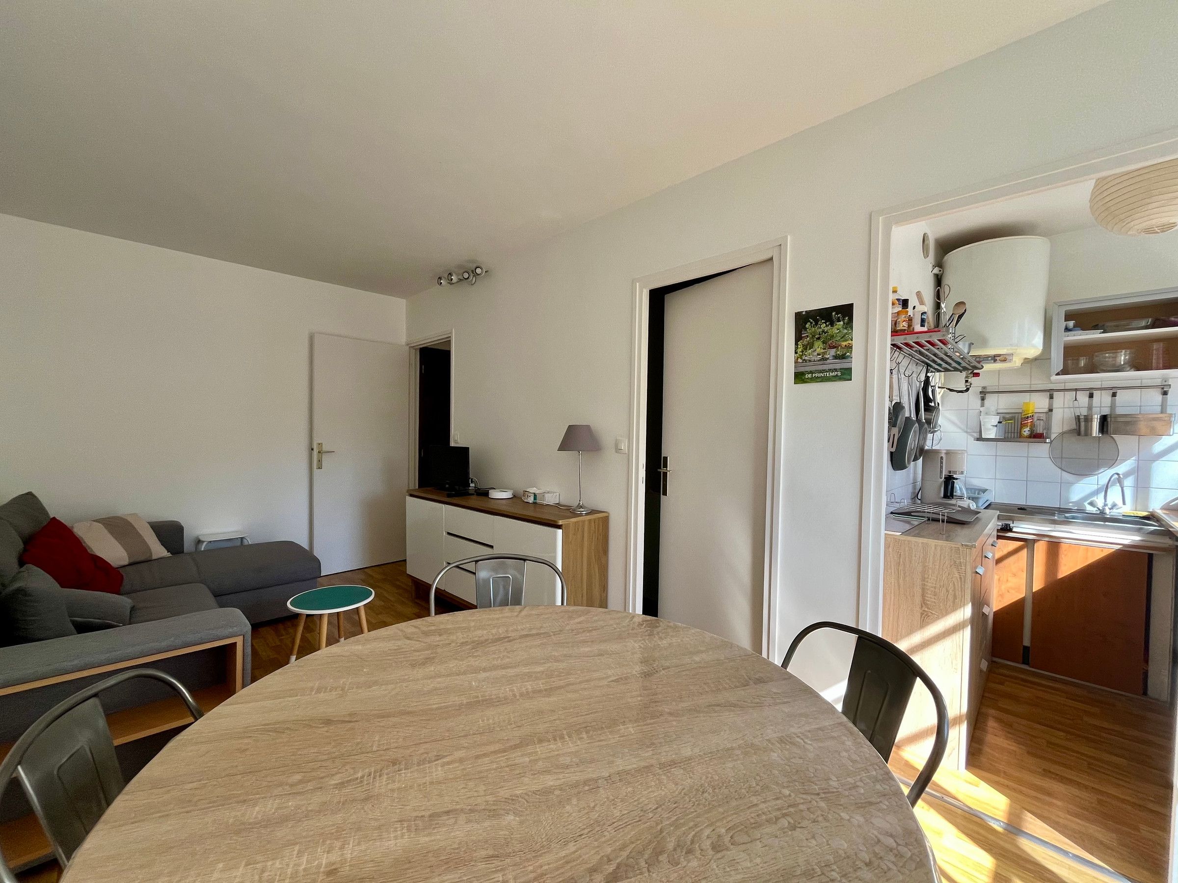 Un espacio habitable compacto con una mesa de comedor, una kitchenette y un sofá.