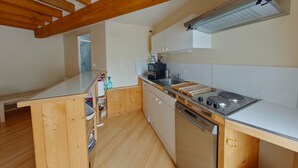 A modern kitchen with wooden beams, a dishwasher, a stove, and a sink. - Cozy 70m² apartment with WIFI near Saint Roch hot springs (La Roche-Posay)