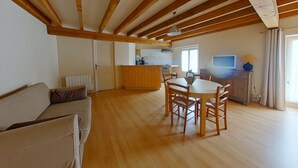 A spacious living area with a wooden ceiling, a dining table with chairs, a sofa, and a kitchen in the background. - Cozy 70m² apartment with WIFI near Saint Roch hot springs (La Roche-Posay)