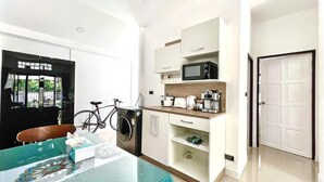 A compact kitchen with a microwave, toaster, and coffee maker, a bicycle, and a table with a tissue box. - Bayok 10 - 2 Bedroom Villa Near Kathu Waterfall (Kathu)
