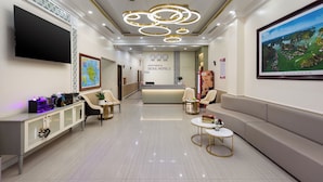 A hotel reception area with a reception desk, seating, a TV, and a large framed picture on the wall. - Cat Ba Seoul 2 Hotel & Apartment (Hai Phong)
